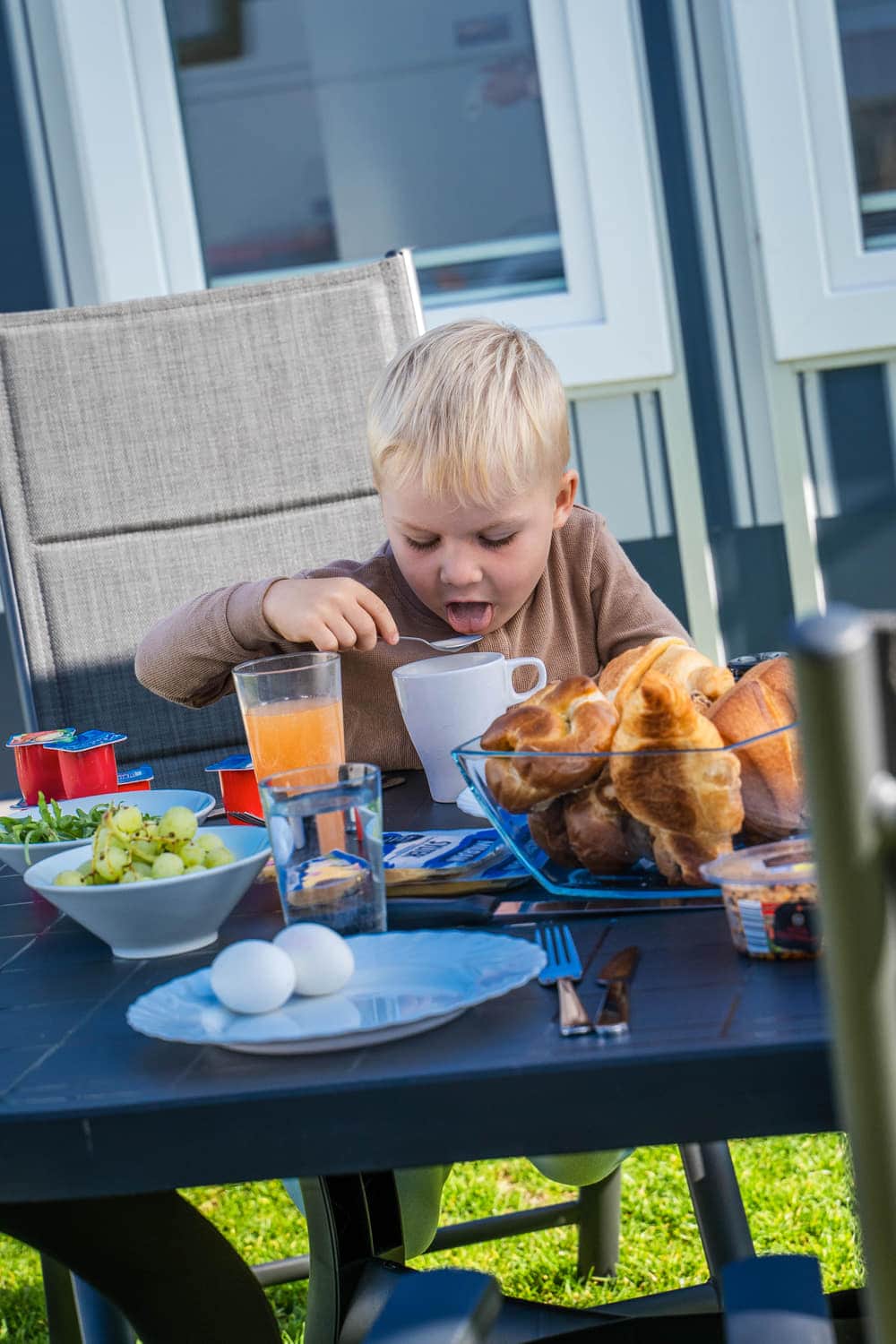 Kind beim Frühstück am Tisch vor dem Wohnwagen