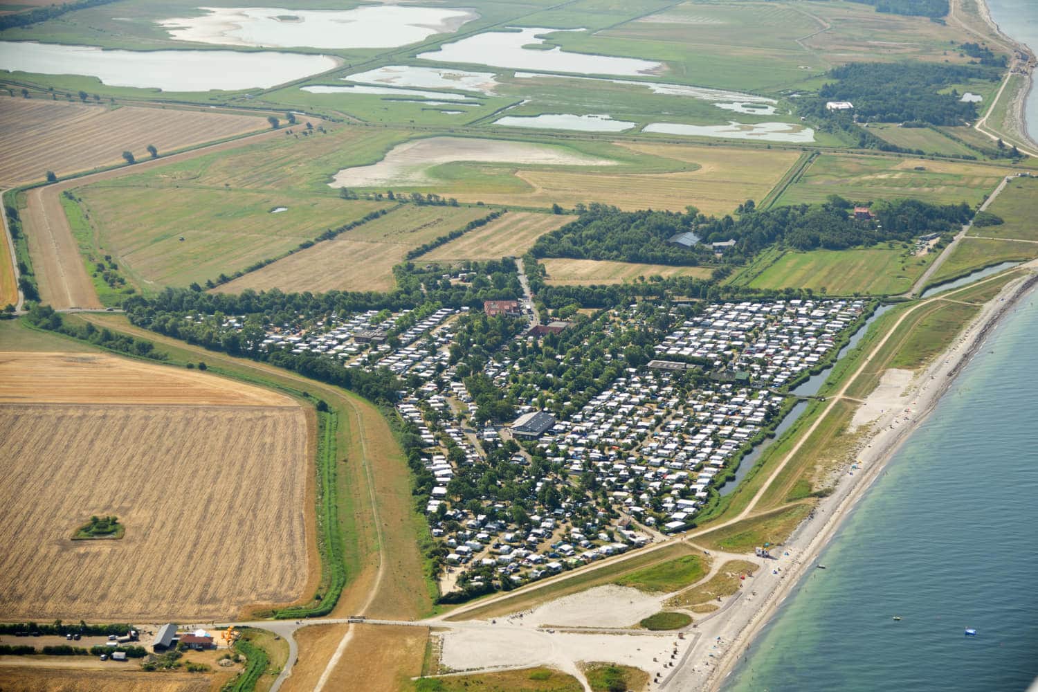 Luftbild von Strand, Deich und Stellplätzen