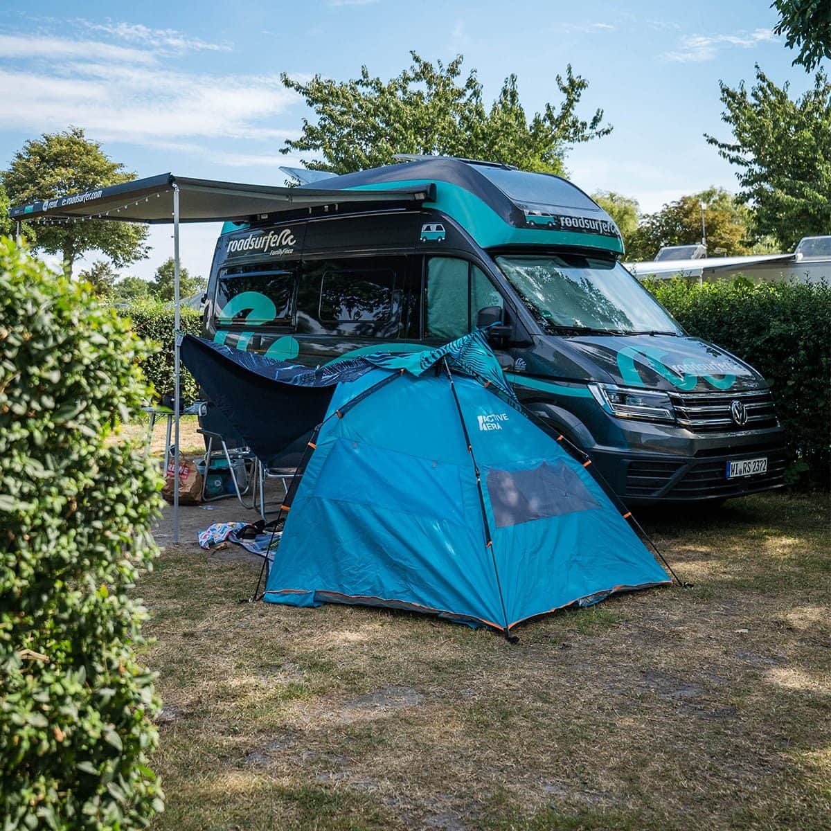 Wohnwagen mit Vorzelt zwischen hohen Hecken auf dem Stellplatz