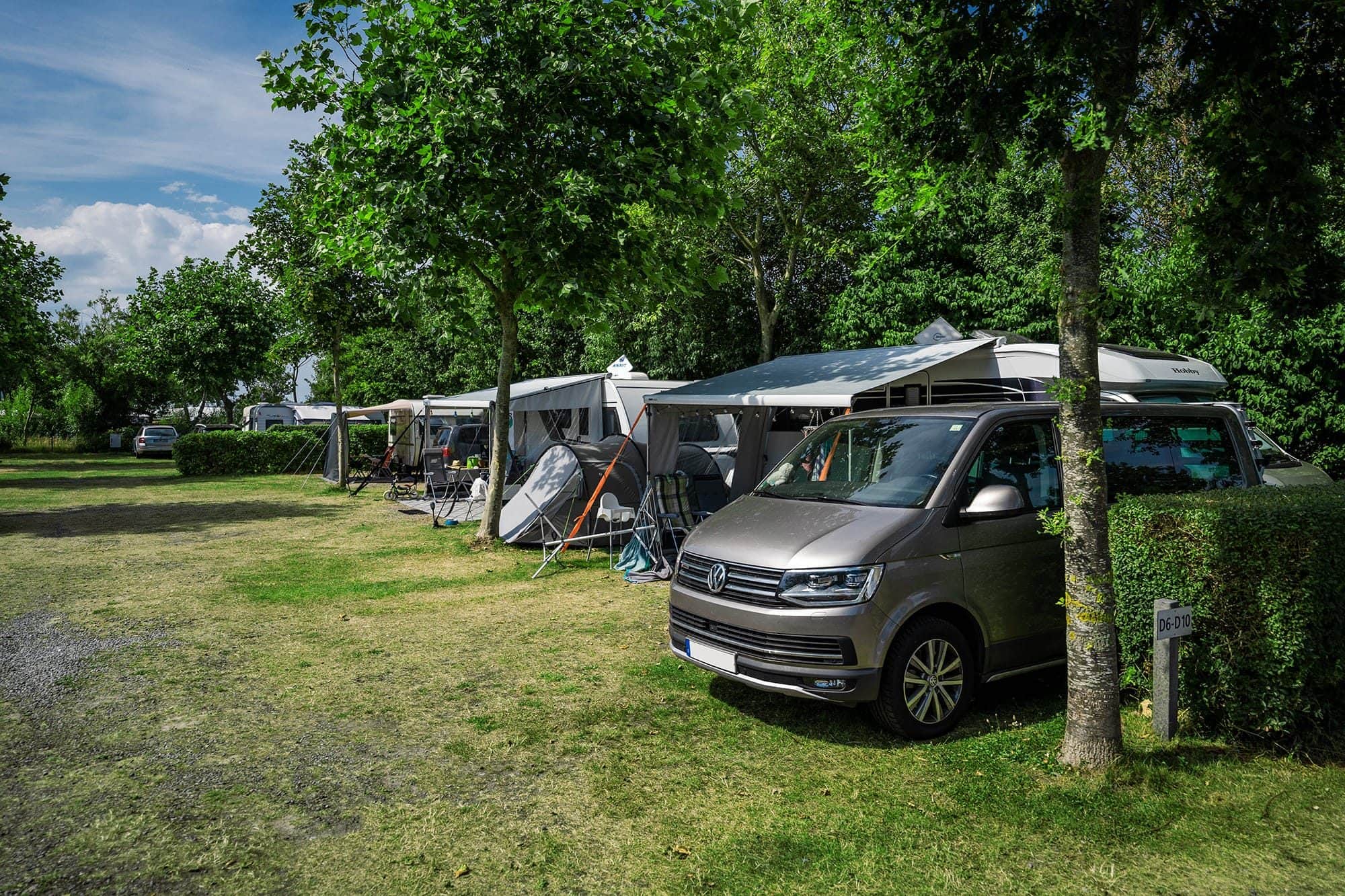 Wohnwagen mit Vorzelt auf einem heckenparzellierten Stellplatz im Grünen