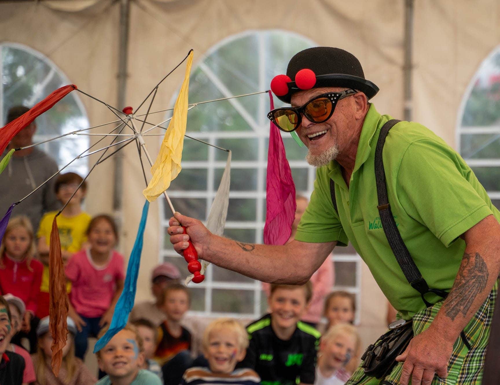 Zauberer begeistert eine Gruppe Kinder im Festzelt